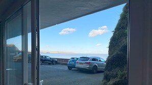 Ein Parkplatz mit mehreren Autos, freiem Blick auf das Meer und einer sanften Graswiese.