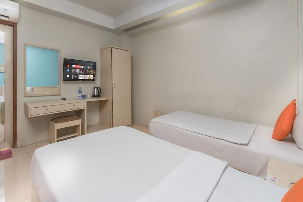 A hotel room with a bed, a desk with a computer, a wardrobe, and a television.