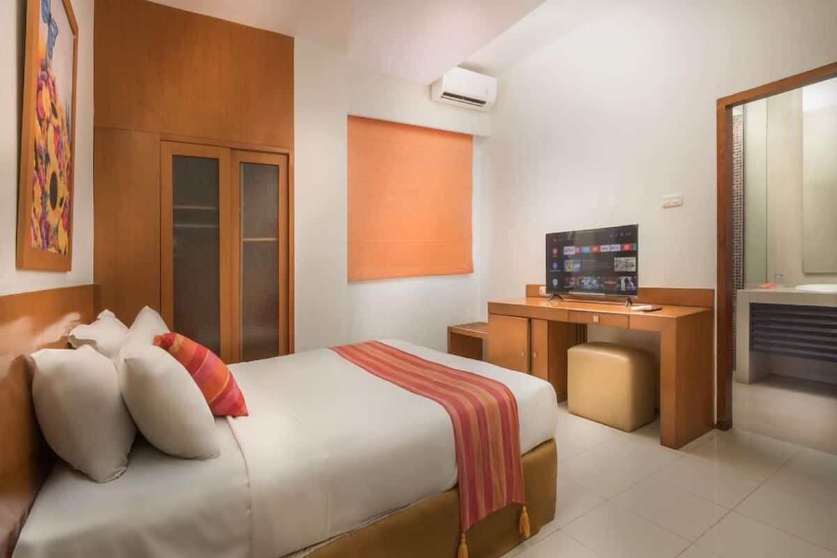 A hotel room with a bed, a desk, a television, and a bathroom.
