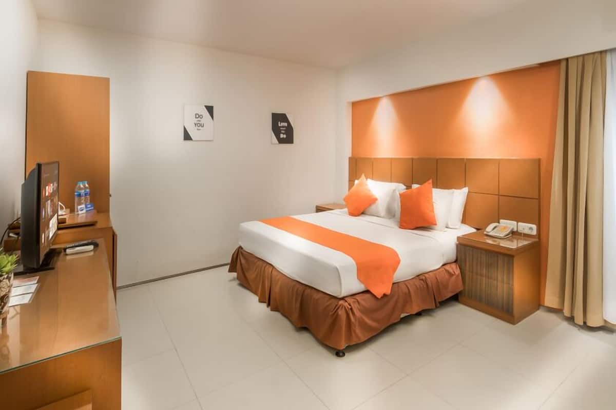 A hotel room with a large bed, a desk with a computer, and a television.