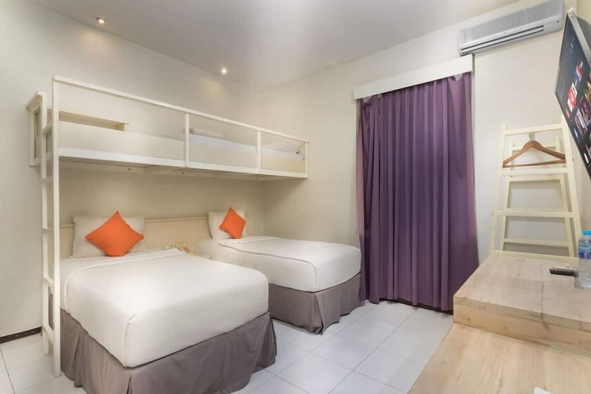 A hotel room with two beds, a desk, and a TV.