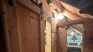 Ambiente interno in legno con soffitto spiovente, un letto e una finestra ben visibile.