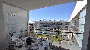 A balcony with a table set for dining, overlooking a residential building. - Beautiful vacation apartment in Roses, Costa Brava. Bright, modern, sleeps 4 people. Well-equipped and well-located. (Roses)