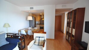 A compact living space with a sofa, a dining table, and a kitchen area. - Beautiful vacation apartment in Roses, Costa Brava. Bright, modern, sleeps 4 people. Well-equipped and well-located. (Roses)