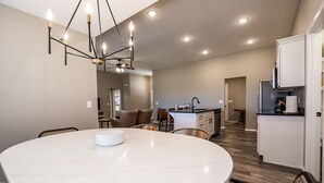 A spacious kitchen with a central island, recessed lighting, and a dining area with a round table.