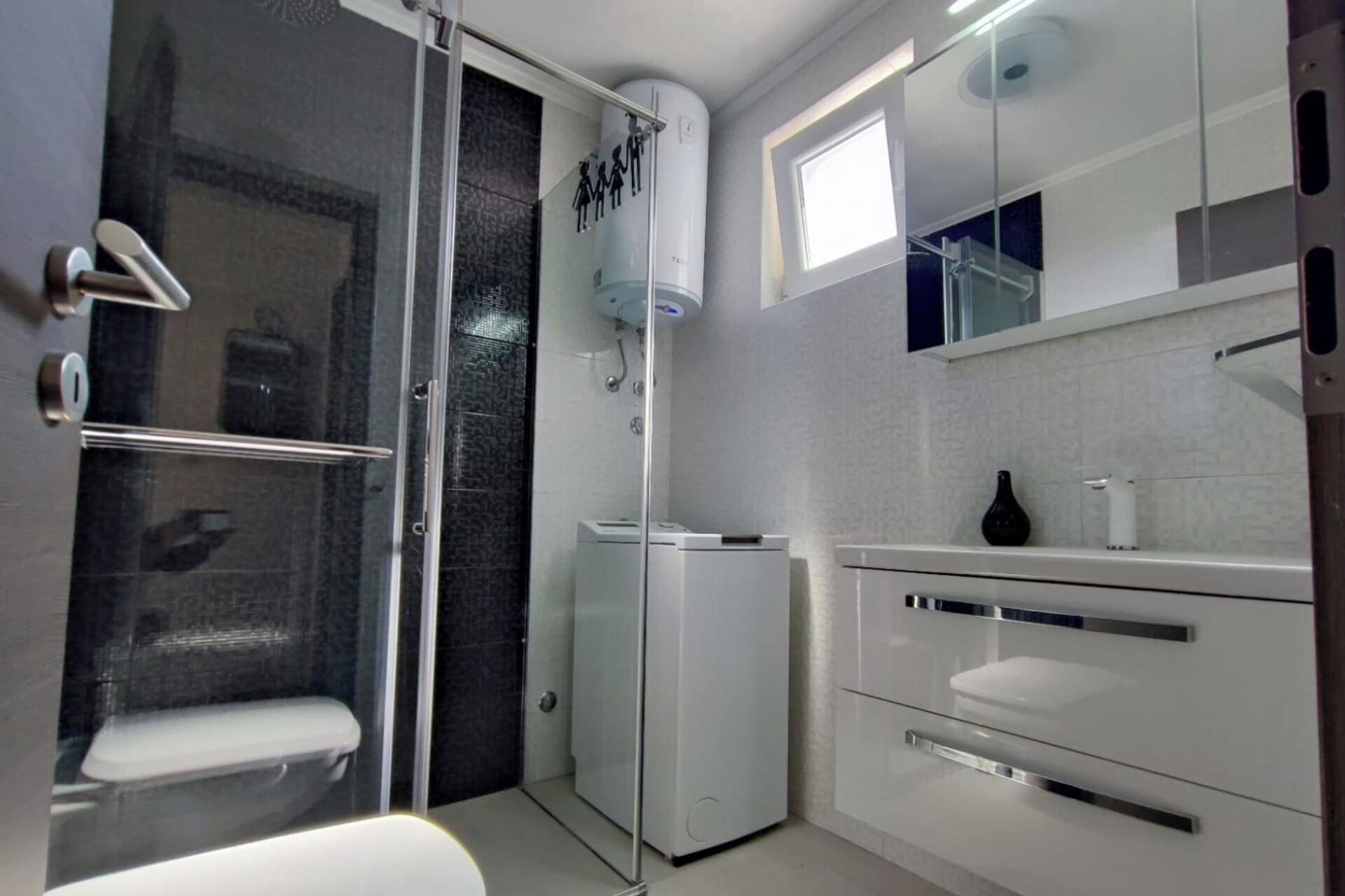 A modern bathroom with a glass shower enclosure, a toilet, a sink, and a mirror.