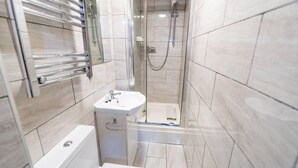 Un bany modern amb plat de dutxa, un lavabo i un vàter.