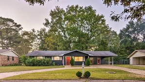 A motel with a central building and two smaller attached units, surrounded by a well-maintained lawn and trees.