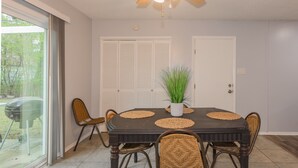 A dining area with a round table, four chairs, a ceiling fan, and a potted plant.