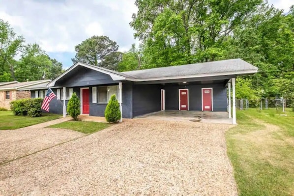 A motel with a gravel driveway, a flag, and a red door.