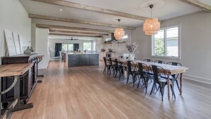 Een ruime keuken met houten balken, een centraal kookeiland en hanglampen.
