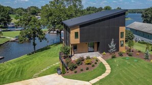 Een modern huis met twee verdiepingen, een plat dak, een groot raam en een verzorgd gazon.