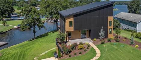 A modern two-story house with a flat roof, a large window, and a well-maintained lawn.