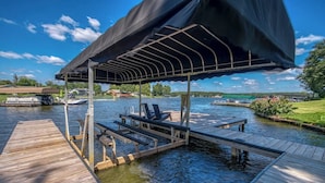 Een houten steiger die zich uitstrekt over het water, met een overdekte zithoek en loungestoelen.