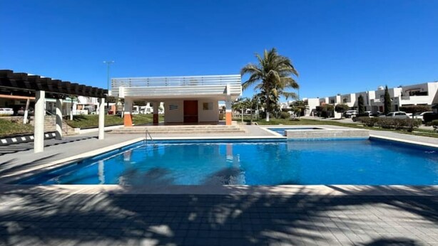 A swimming pool with a covered area and a building in the background. - Relaxing house with pool & self check-in (Mazatlán)