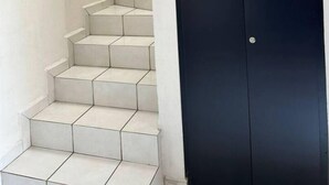 A staircase leading to a dark door, with a light-colored wall on one side. - Relaxing house with pool & self check-in (Mazatlán)