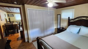 Een slaapkamer met een bed, nachtkastje, houten plafond en een inloopkast.