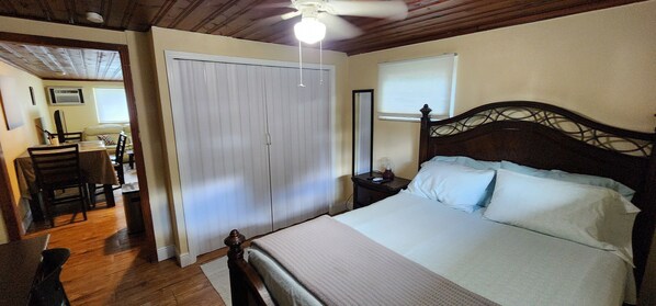 A bedroom with a bed, a nightstand, a wooden ceiling, and a closet.