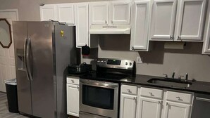 Una cocina con armarios blancos, electrodomésticos de acero inoxidable y suelo con motivo de espiga.