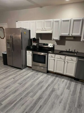 A kitchen with white cabinets, stainless steel appliances, and a herringbone-patterned floor. - Private Apartment in Southbury 101 (Southbury)