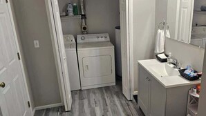 Un lavadero pequeño con lavadora y secadora, un lavabo con artículos de aseo y un espejo sobre el lavabo.