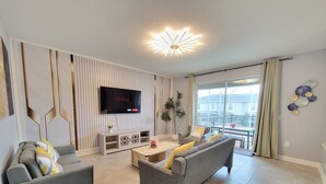 Ein modernes Wohnzimmer mit zwei grauen Sofas, einem Couchtisch und einem an der Wand befestigten Fernseher.