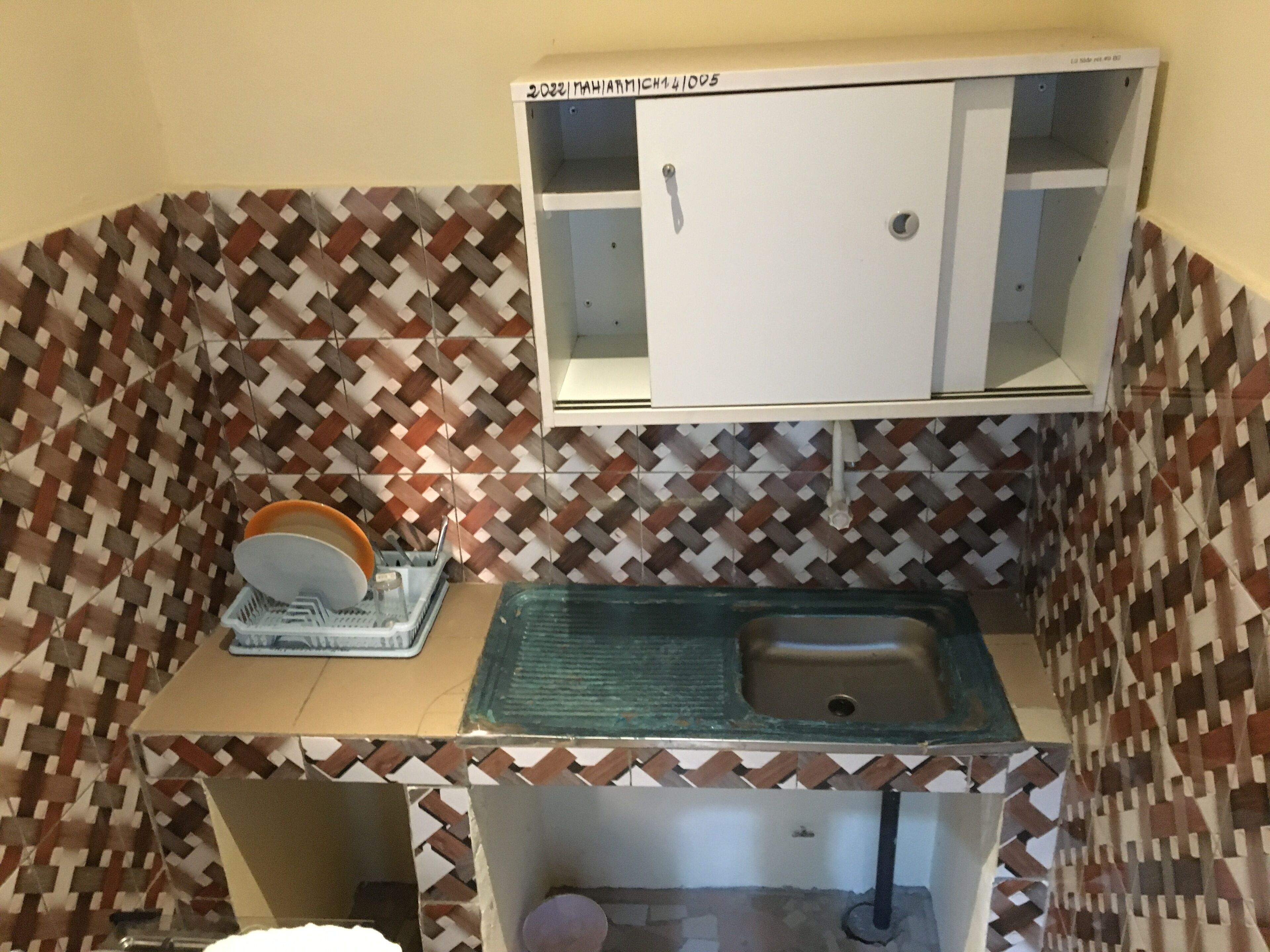 A bathroom with a patterned tile backsplash, a white cabinet with a mirror, and a sink with a green basin.