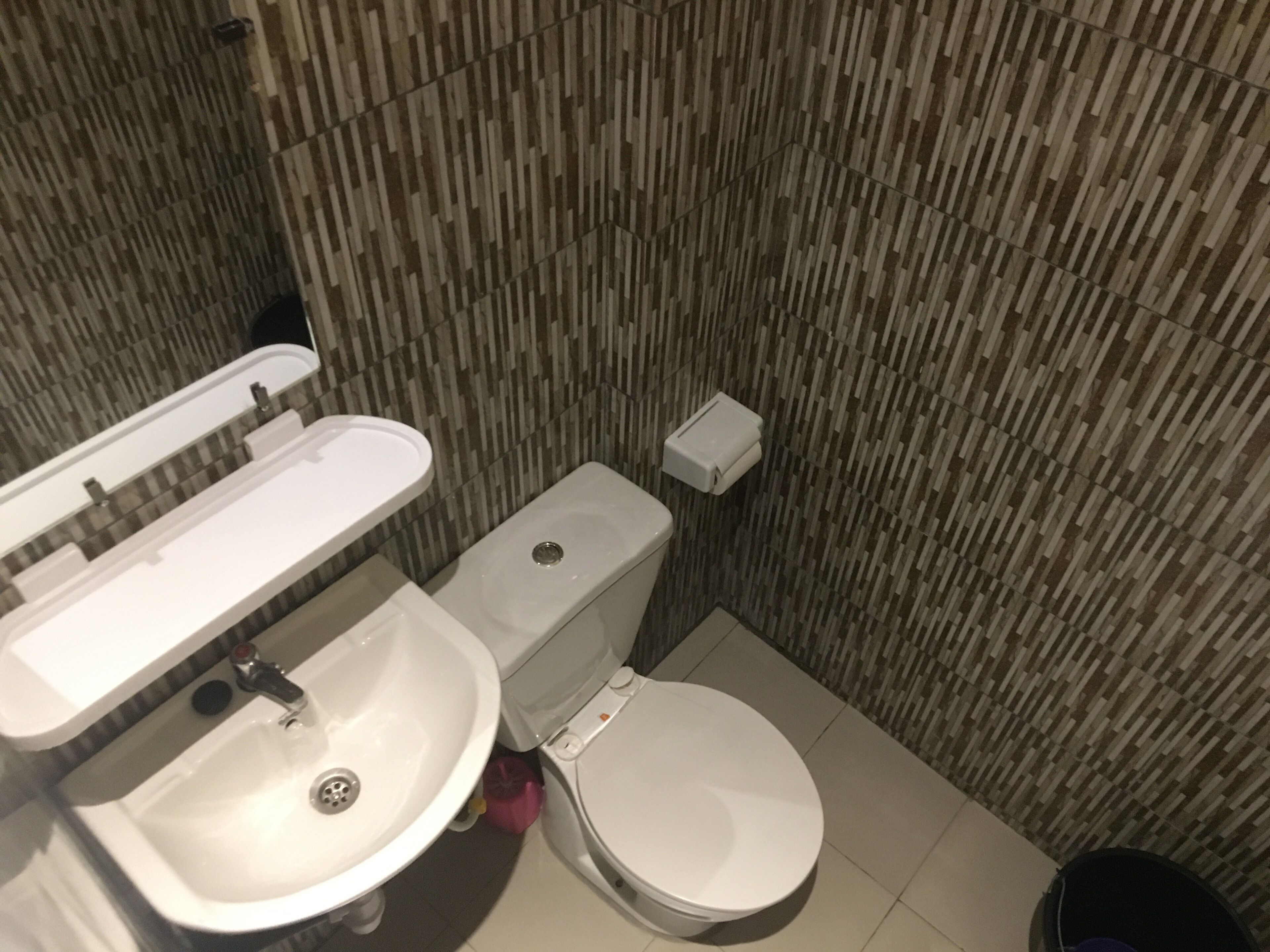 Une salle de bain avec un lavabo blanc, des toilettes et un distributeur de savon fixé au mur.