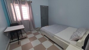 A small, single-room accommodation with a bed, a desk, and a chair. - Residence MaryHouse (Cotonou)