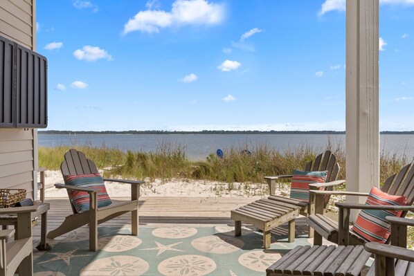 Terraza en la playa con sillas Adirondack y vista al océano.