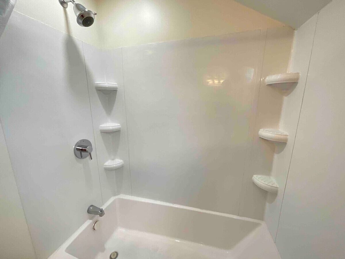 A bathroom with a bathtub, a showerhead, and a toilet.