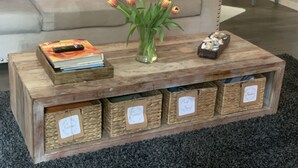 Una mesa de centro de madera con un jarrón de tulipanes, un libro y un adorno pequeño.