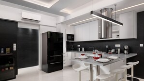 A modern kitchen with a central island, bar stools, and a built-in microwave. - Rhodes Skyline Suite with out Door Jacuzzi Sea View A2 (Rhodes)