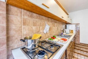 A modern kitchen with a gas stove, a pot of spaghetti, and a variety of fresh vegetables on the counter. - Green Hill Zagreb - Apartment Zen, Zagreb, Croatia (Zagreb)