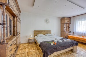 Un dormitorio con cama de madera, mesita de noche, cómoda, tocador y ventana con cortinas.