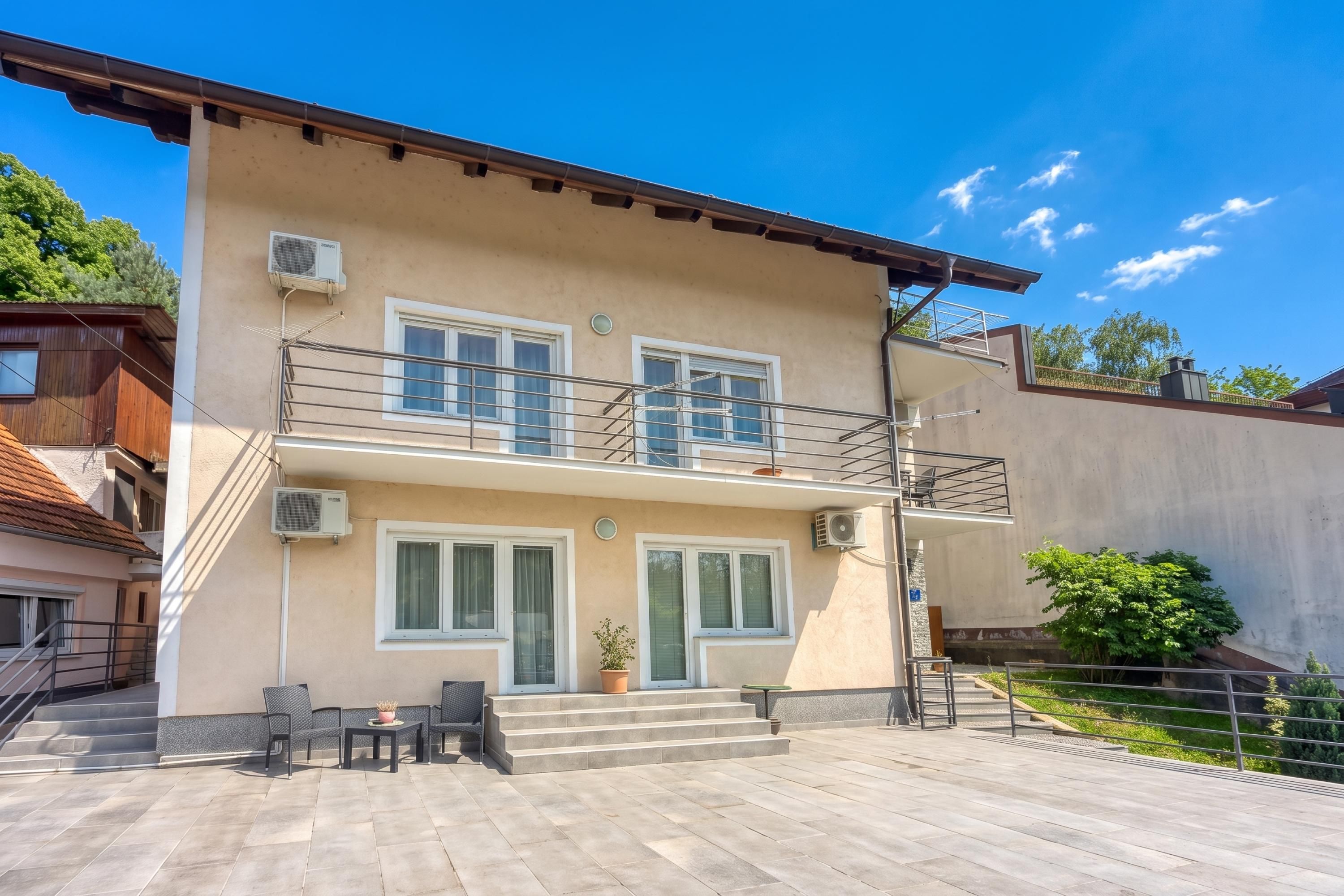 A two-story building with a balcony, a staircase, and a patio area with outdoor furniture.