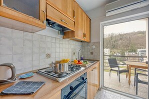 Eine moderne Küche mit Holzschränken, einem Gasherd und Blick ins Freie.