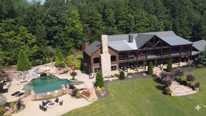Ein großes Chalet mit Pool, Außensitzgelegenheiten und einem Kamin aus Stein.