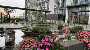 A modern urban courtyard with a water feature, potted plants, and a playground. - Vinhomes Metropolis 3Brs  (Hanoi)