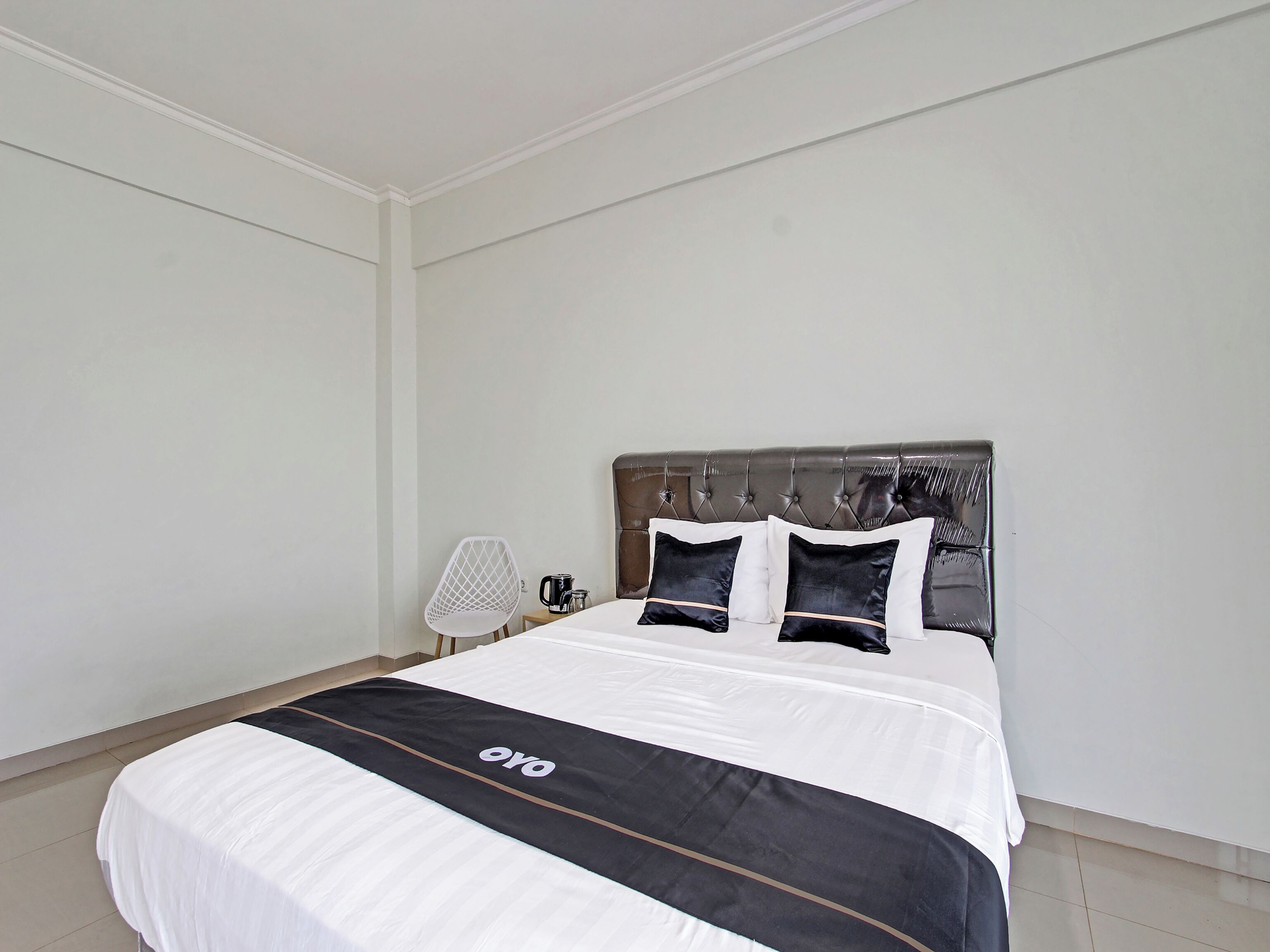 A neatly made bed with a black and white bedspread, a tufted headboard, and two black pillows.