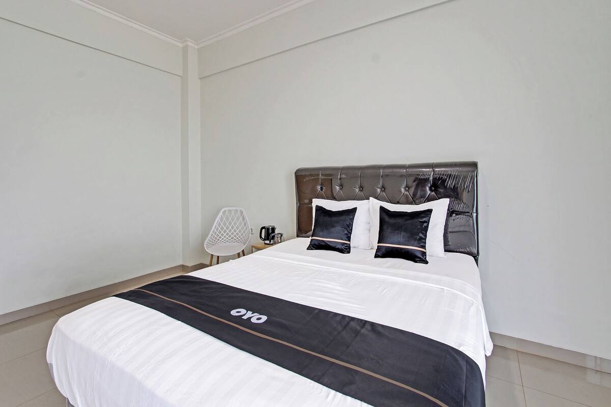 A neatly made bed with a black and white bedspread, a tufted headboard, and two black pillows.