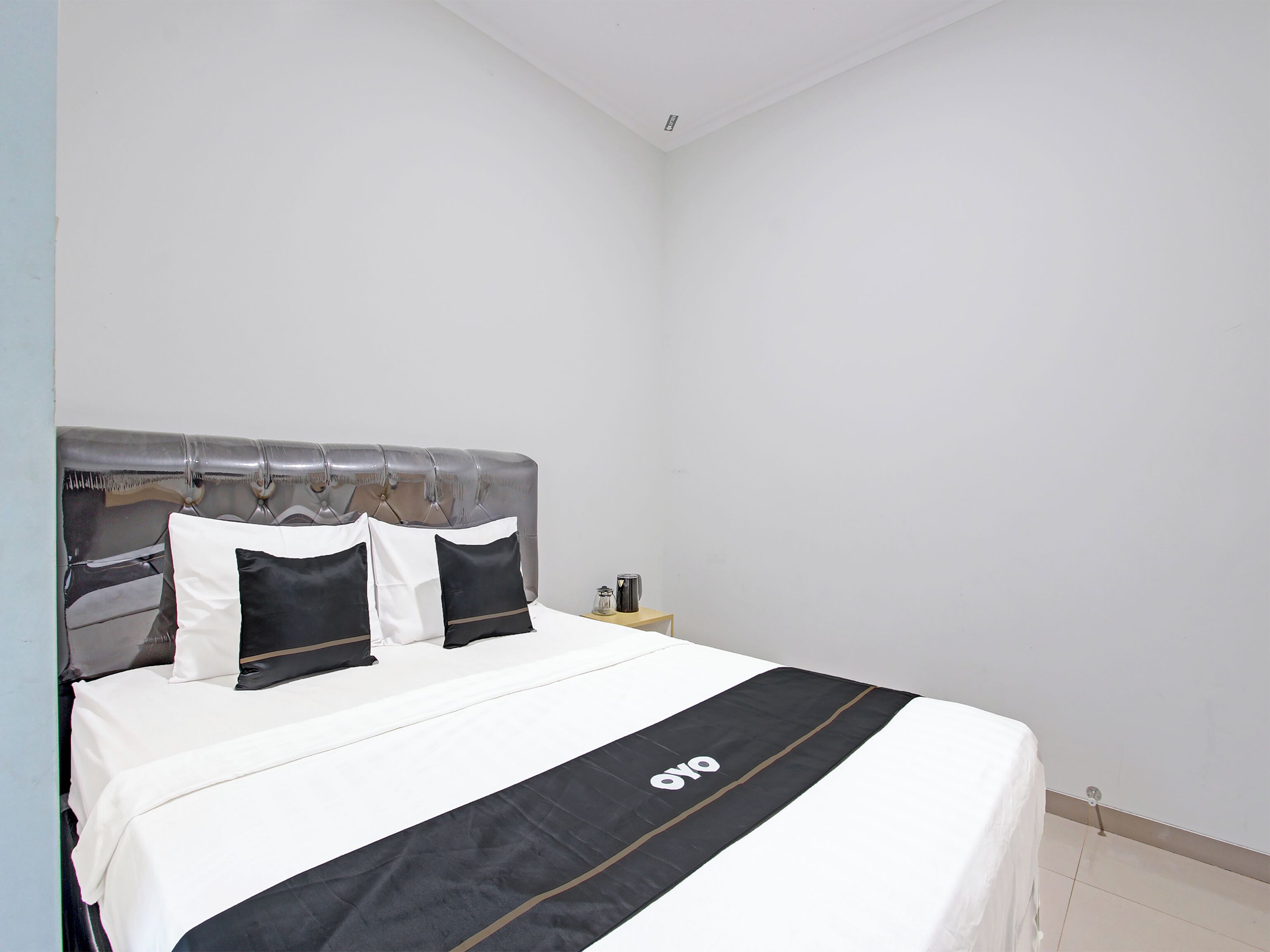 A neatly made bed with a black and white bedspread and a black and white pillow arrangement.