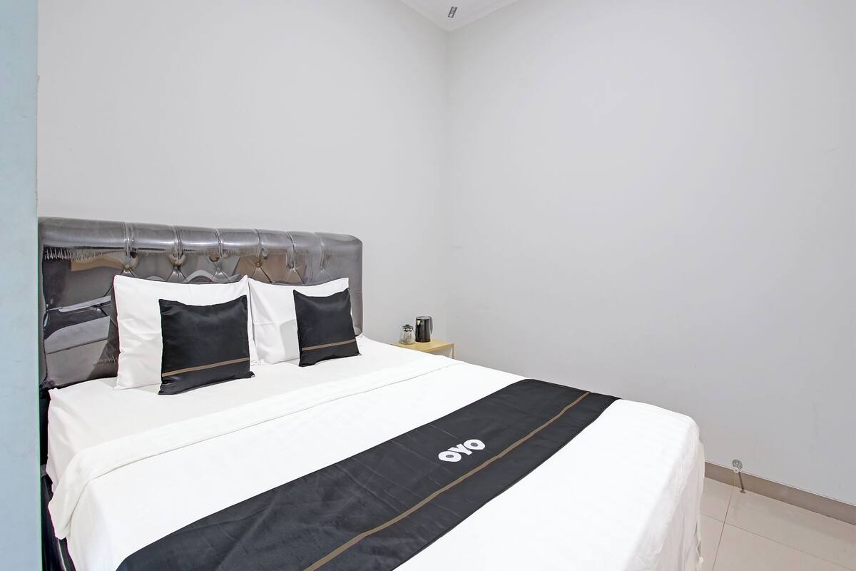 A neatly made bed with a black and white bedspread and a black and white pillow arrangement.