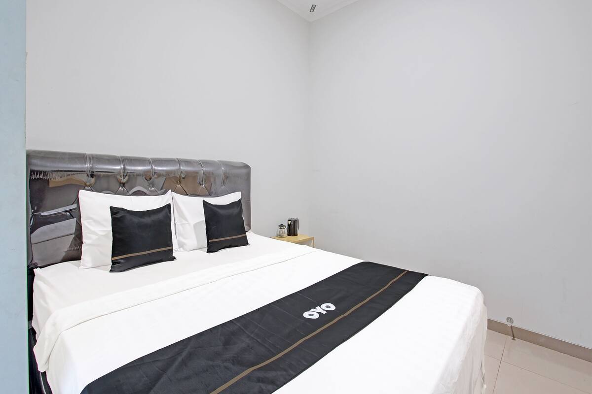 A neatly made bed with a black and white bedspread and a black and white pillow arrangement.
