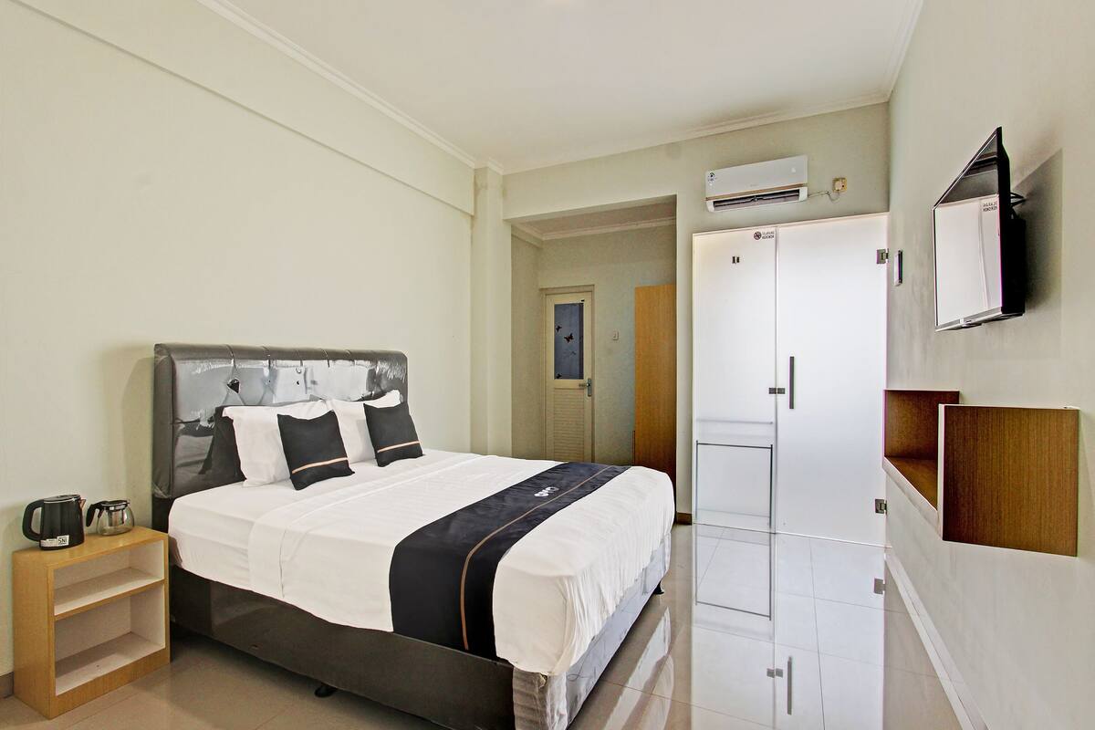 A hotel room with a bed, a nightstand, a wardrobe, and a mirror.