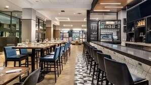A modern restaurant with a bar area, long tables with chairs, and a tiled floor. - Gateway to Columbus' Wonders! Pet-friendly Unit Close to Victorian Village (Columbus)