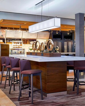A modern bar area with a central island, bar stools, and a menu board in the background. - Discover Stylish Comfort! Outdoor Pool & Free Airport Shuttle! (Morrisville)