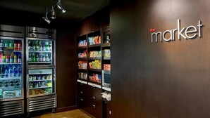 Ein gekühlter Kiosk mit verschiedenen Getränken und Snacks, und eine Wand mit dem Schriftzug "the market".