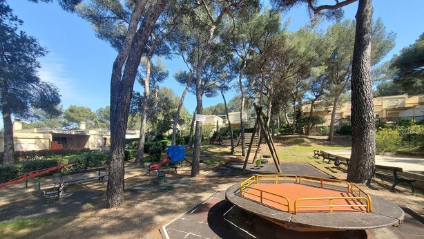 A playground with a slide, swings, and a climbing structure surrounded by trees and a paved area. - 2-bedroom club villa with large terrace in holiday residence (SIX FOURS LES PLAGES)
