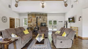 A spacious living room with two sofas, a coffee table, and a stone fireplace. - Isabelle Creek Haven - Ultimate Group Getaway (Bay City)